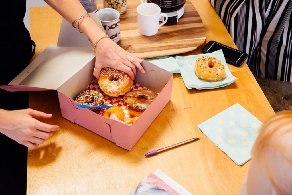 Cropped view of colleagues sharing doughnuts in cake box