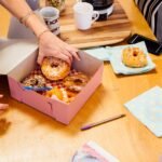 Cropped view of colleagues sharing doughnuts in cake box